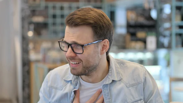 Portrait of Young Man Coughing in Cafe