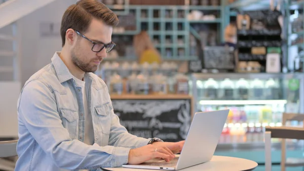 Jeune homme créatif travaillant sur ordinateur portable à Cafe — Photo