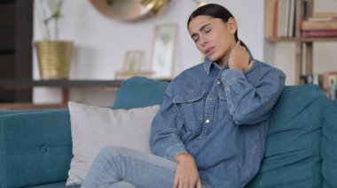 Boyun ağrısı olan yorgun Latin Kadın Koltukta oturuyor 