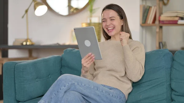 Succès, Jeune femme célébrant sur tablette sur canapé — Photo