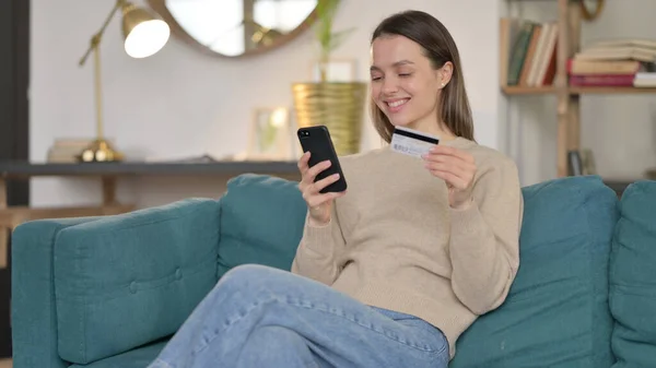 Succès des achats en ligne sur Smartphone par Young Woman sur Sofa — Photo