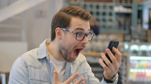 Porträt eines jungen Mannes, der auf dem Smartphone feiert — Stockfoto