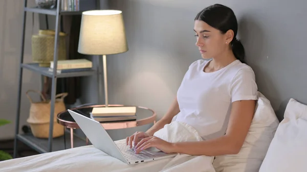 Młoda Latynoska pracuje na laptopie w łóżku — Zdjęcie stockowe