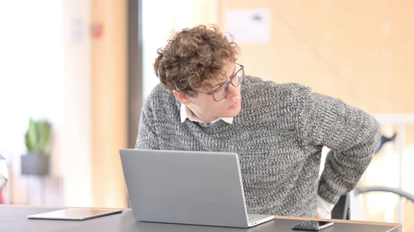 Jeune homme avec douleur au dos en utilisant un ordinateur portable au travail — Photo