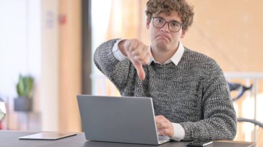 Dizüstü bilgisayarlı genç adam Başparmakları Aşağı Gösteriyor 