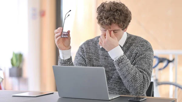 仕事でノートパソコンを使って頭痛のある若い男 — ストック写真