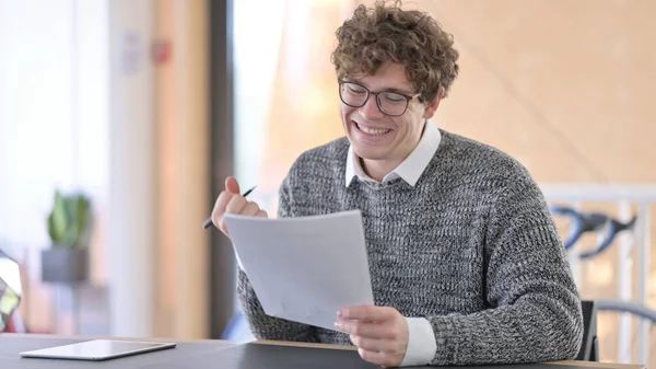 Un jeune homme excité célèbre son succès sur les documents, — Photo