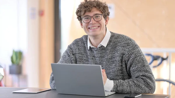 Jonge man met laptop glimlachend naar camera — Stockfoto