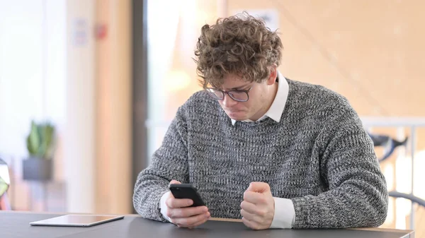 Jeune homme malheureux avec perte sur Smartphone au travail — Photo