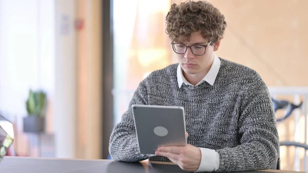 Jeune homme concentré utilisant une tablette numérique au travail — Photo