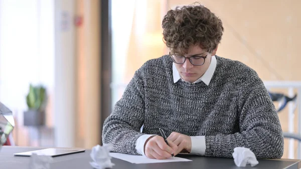 Teleurgesteld jonge man probeert op papier op het werk — Stockfoto