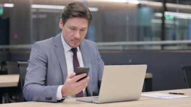 Orta Çağ İşadamı Ofiste Dizüstü bilgisayar ve Akıllı Telefon üzerinde çalışıyor 