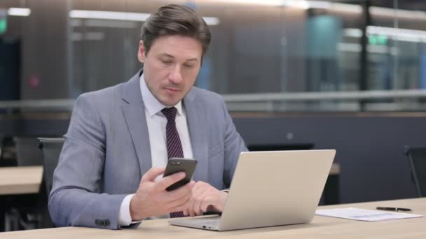 Empresário de Idade Média com Laptop Talking no Smartphone — Vídeo de Stock