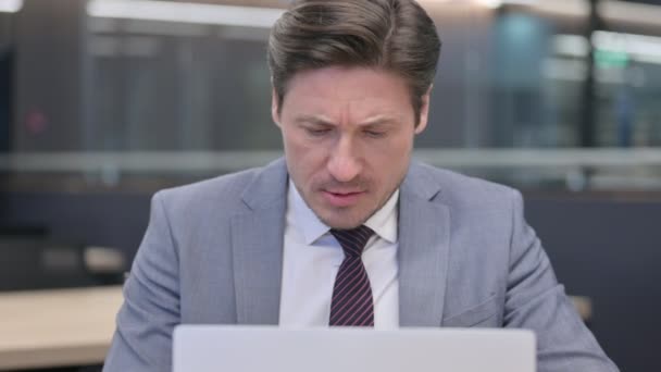 Primer plano del hombre de negocios de mediana edad con el ordenador portátil que tiene dolor de cabeza — Vídeos de Stock