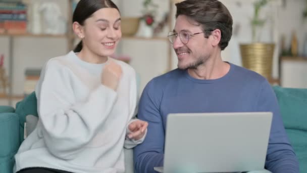 Chamada de vídeo on-line no laptop por casal latino sentado no sofá — Vídeo de Stock