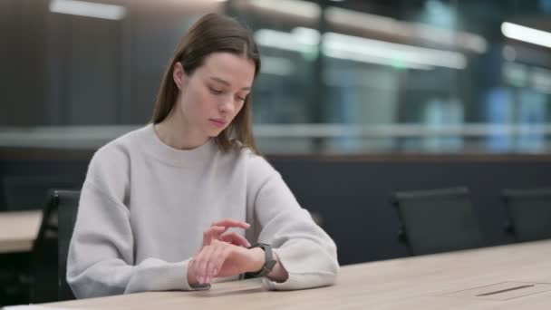 Hermosa mujer usando reloj inteligente en la oficina — Vídeo de stock