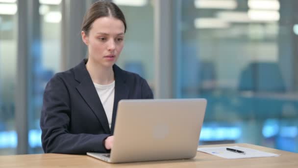 Молодая предпринимательница, работающая над ноутбуком в офисе — стоковое видео