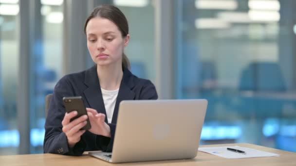 Jovem empresária trabalhando no smartphone e laptop no escritório — Vídeo de Stock