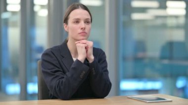 Güzel genç iş kadını ofiste oturuyor ve düşünüyor. 