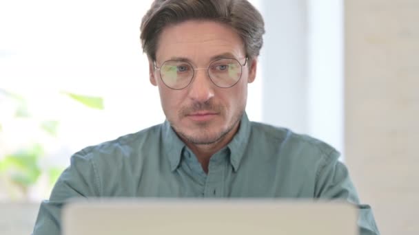 Porträt eines Mannes mittleren Alters mit Laptop, der in die Kamera blickt — Stockvideo