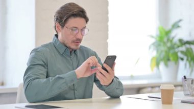 Ofisteki Akıllı Telefon 'da Orta Yaşlı Adam Başarı Kutlaması 