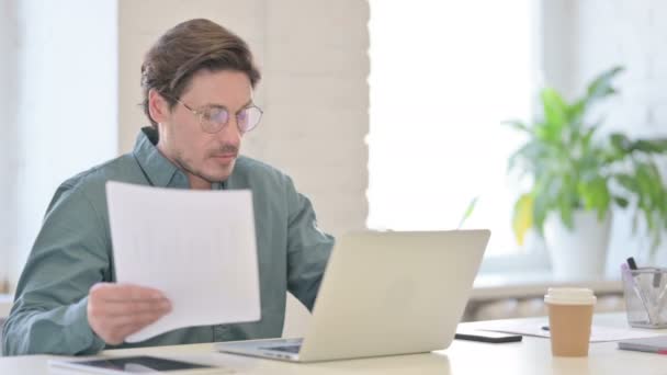 Людина з ноутбуком читання документів в офісі — стокове відео