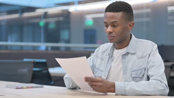 Hombre africano leyendo documentos en la oficina — Vídeos de Stock