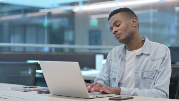 Afrikai férfi laptoppal, akinek nyaki fájdalma van — Stock videók