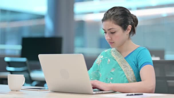 Donna indiana sorridente alla fotocamera durante l'utilizzo del computer portatile — Video Stock