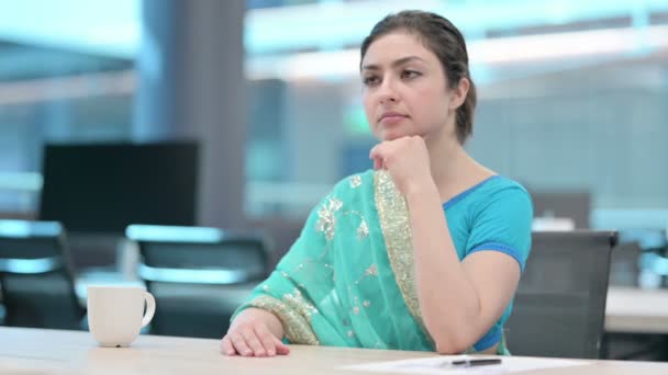 Młoda Hinduska kobieta myśląca podczas siedzenia w pracy — Wideo stockowe