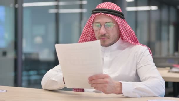 Araber mittleren Alters liest Dokumente im Büro — Stockvideo