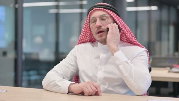 Арабский мужчина средних лет разговаривает по смартфону в офисе — стоковое видео