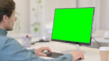 Yeşil Renkli Anahtar Ekranı olan Masaüstü kullanan adam
