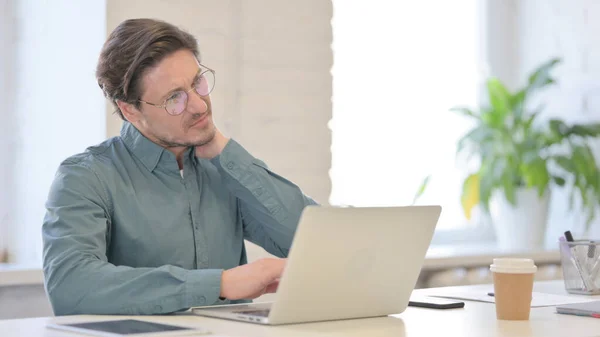 Hombre de mediana edad con portátil que tiene dolor de cuello — Foto de Stock