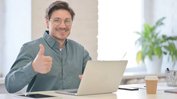 Pulgares hacia arriba por el hombre de mediana edad con el ordenador portátil en la oficina — Foto de Stock