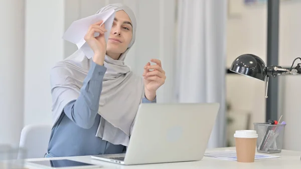 Jonge Arabische vrouw met laptop vliegend papier vliegtuig — Stockfoto