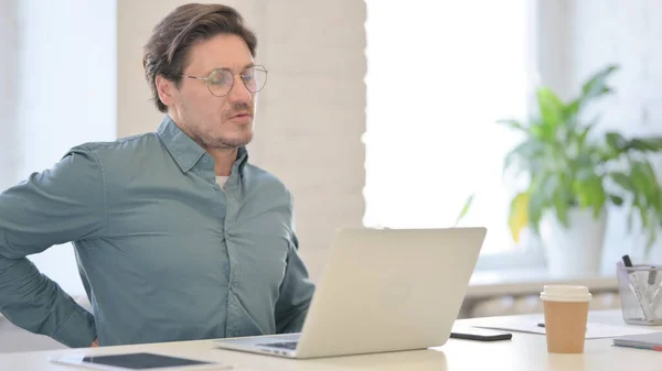 Hombre de mediana edad con portátil que tiene dolor de espalda — Foto de Stock