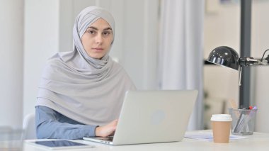Dizüstü bilgisayarlı Çekici Genç Arap Kadın Kameraya Bakıyor 