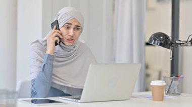 Ofiste akıllı telefon kullanan çekici genç bir Arap kadın. 