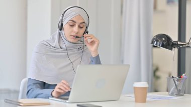 Laptop 'u olan genç Arap Kadın Kulaklıkla Konuşuyor 