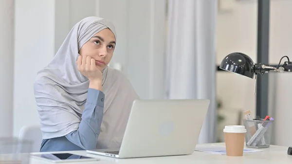 Jovem mulher árabe Pensando ao usar laptop no escritório — Fotografia de Stock