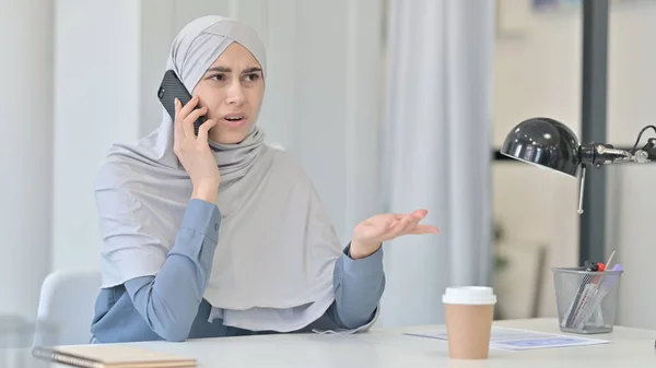 Mulher árabe irritada enquanto fala no smartphone no escritório — Fotografia de Stock