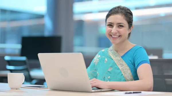 Indiska kvinna ler mot kameran när du använder laptop — Stockfoto