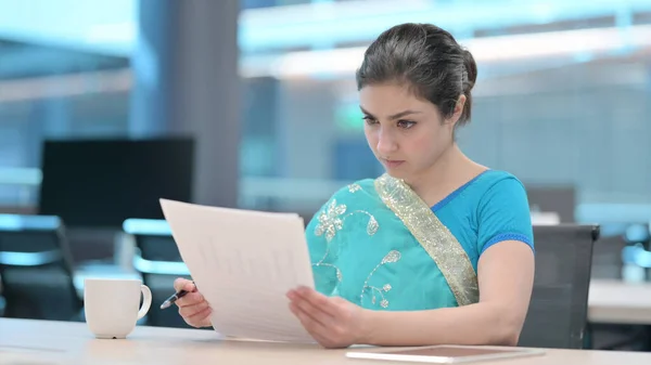 Young Indian Woman Reading Papers at Work