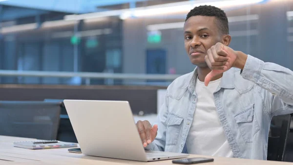 Polegares para baixo por homem africano com laptop no escritório — Fotografia de Stock