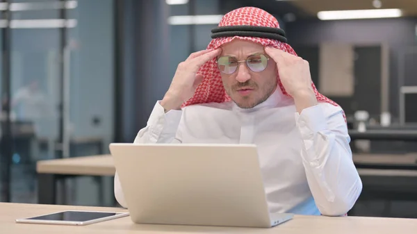 Medelålders arabisk man med bärbar dator med huvudvärk — Stockfoto