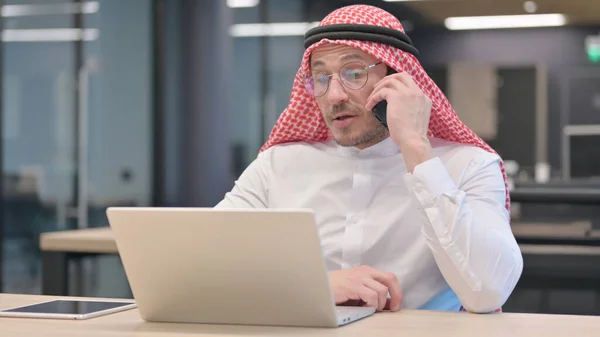 Medelålders arabisk man med bärbar dator Talar på smartphone — Stockfoto