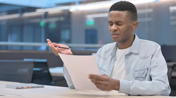 Afrikanischer Mann reagiert auf Verlust beim Lesen von Dokumenten — Stockfoto