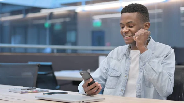 Afrikaner feiert Erfolg auf Smartphone im Büro — Stockfoto