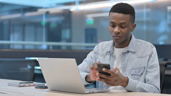 Afrikaner mit Laptop und Smartphone bei der Arbeit — Stockfoto